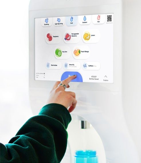 A hand selecting a flavor on a Bevi hydration unit's touchscreen.