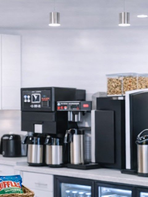 Airpot brewers and a bean-to-cup machine on an office coffee counter.